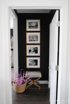 a hallway with pictures on the wall and a basket full of flowers in front of it