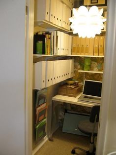 an open closet with a laptop computer on the desk and bookshelves in it