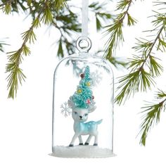 a glass ornament hanging from a tree filled with snow and a little deer