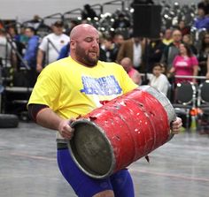 a man is carrying a large drum in front of an audience at a concert or show