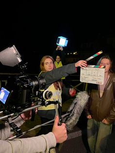 a group of people standing next to each other in front of a camera set up