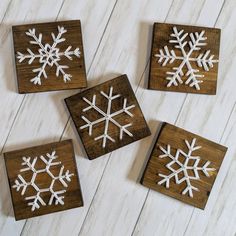 four wooden snowflakes are sitting on a white wood floor and one is cut out