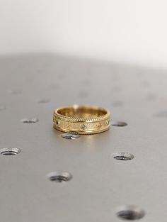 two gold wedding bands sitting on top of each other with diamonds in the middle and small dots around them