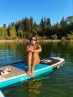 a woman sitting on top of a surfboard in the water with her legs crossed