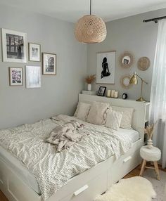 a white bed sitting in a bedroom next to a window with pictures on the wall