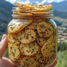 a hand holding a jar filled with crackers