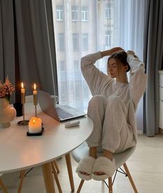 a woman sitting at a table with her feet up in the air while wearing slippers