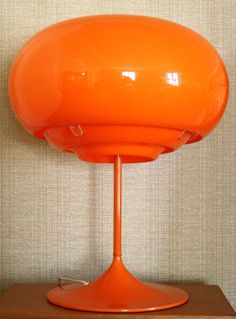 an orange table lamp sitting on top of a wooden shelf