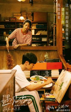 a man sitting in front of a book shelf holding a plate with food on it