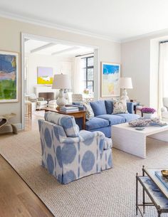 a living room with blue and white furniture in the center, along with two lamps on either side of the couches