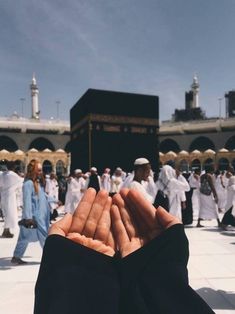 two hands folded in front of a large group of people standing around the kabab