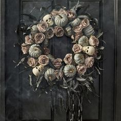 a wreath with skulls, roses and leaves is on the front door to a house