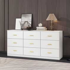 a white dresser sitting next to a lamp on top of a wooden floor