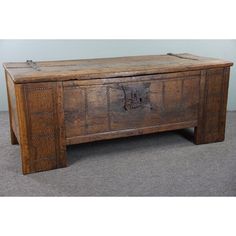 an old wooden chest with carvings on the front and sides, sitting on carpeted floor