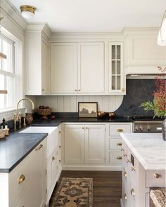 a kitchen with white cabinets and black counter tops, an area rug on the floor