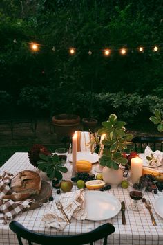 an outdoor table set with plates, candles and fruit on it for a festive dinner