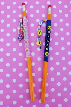 two pencils sitting on top of a polka dot tablecloth with beaded decorations