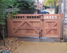 a large wooden gate in front of a brick building with a car parked behind it