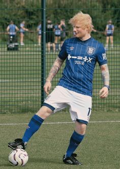 a man in blue and white uniform kicking a soccer ball