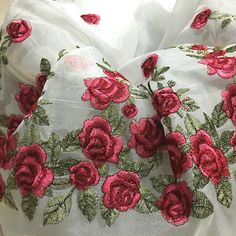 a white and red pillow with pink flowers on it