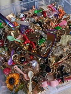 a plastic container filled with lots of different types of charms and brooches on top of a table