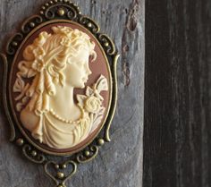 Beautiful cream cameo with a brown background set in antique brass paired with antique brass chain. Cameo features a detailed Victorian girl with flowers, curls in her hair and pearls around her neck. Details: Pendant measures approx 2.5 inches (6.35cm) Necklace measures 24 inches (55.88cm) Chain and setting are plated Cameo is hard, matte resin Want a shorter chain? Just leave a note to seller at checkout for me and I can adjust it for you, no extra charge. Thank you for shopping Delicate Indus Brown Victorian Jewelry Gift, Victorian Brown Necklace For Gift, Victorian Cream Jewelry For Gift, Victorian Cream Jewelry For Gifts, Victorian Cream Jewelry Gift, Victorian Style Cream Jewelry Gift, Gift Ideas Mothers Day, Girl With Flowers, Gift Ideas For Mom