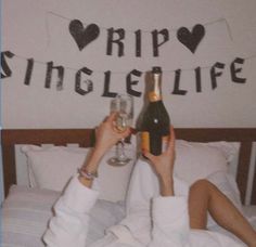 a person laying in bed with two glasses of wine and a sign that says trip single life