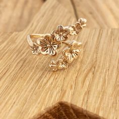 a gold ring with flowers on it sitting on a wooden table next to a piece of wood