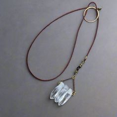 a long necklace with three crystal pieces hanging from it's side on a brown cord