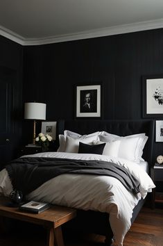 a black and white bedroom with pictures on the wall above the bed, along with two nightstands