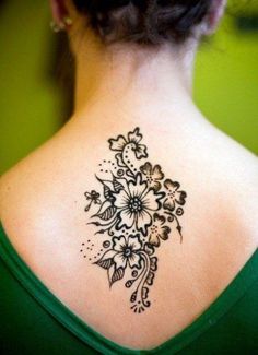 the back of a woman's neck with an intricate tattoo design on her shoulder