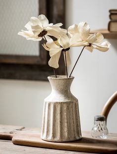 a white vase filled with flowers on top of a wooden table