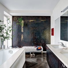 a large bathroom with two sinks and a bathtub next to a plant in the corner