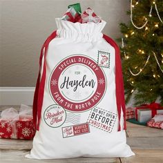 a white bag sitting on top of a wooden floor next to a christmas tree and presents