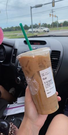 a person holding up a starbucks drink in their car