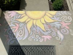 a sun painted on the side of a building next to a street drain grate