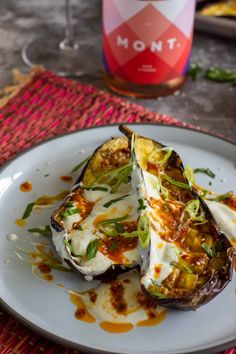 an eggplant dish on a plate next to a bottle of wine