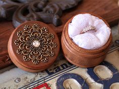 two wooden boxes with wedding rings in them on a table next to other decorative objects