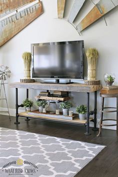 a flat screen tv sitting on top of a wooden stand in a living room next to a rug