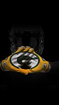 the green bay packers football gloves are shown in front of a helmet and black background