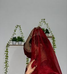 a woman in a red sari covering her face with a veil over her head