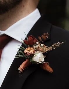 a man wearing a suit and tie with flowers on it's lapel pin