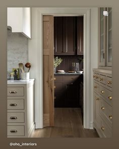 an open door leading to a kitchen with wooden floors and white cabinetry on the walls