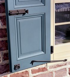 a blue door is open in front of a brick wall with a window on it