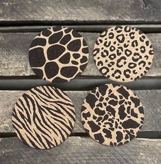 four animal print coasters sitting on top of a wooden bench