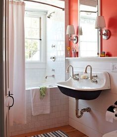 a bathroom with an orange wall and white tile on the floor, along with a black and white rug