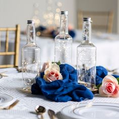 the table is set with two empty bottles and blue napkins, silverware, and flowers