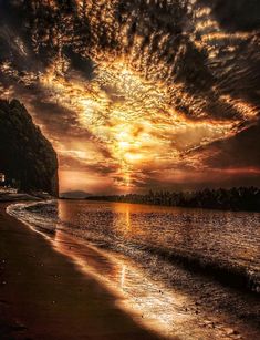 the sun is setting at the beach with waves coming in from the water and clouds