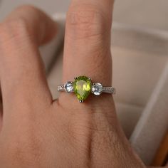 This ring features a 6*9mm pear cut natural peridot sterling silver finished with rhodium. Customization is available. It is made by hand, and it will take about 7 days to finish the ring after your payment is completed. Main stone: natural peridot weight: Approx 1.33 ct Metal type: sterling silver finished with rhodium Accent stone: cz Customization is available, I also can make it with 14k solid gold (white or yellow or rose) and diamond accent stone, just feel free to contact me. Any question Silver Birthstone Ring With Peridot And Accent Stones, Silver Peridot Birthstone Ring With Accent Stones, Silver Pear Shaped Ring With Center Stone, Green Teardrop Ring For May Birthstone, Teardrop Green May Birthstone Ring, Green Teardrop May Birthstone Ring, Sterling Silver Pear-shaped Ring For Anniversary, Sterling Silver Pear Shaped Ring For Anniversary, Green Topaz Sterling Silver Promise Ring