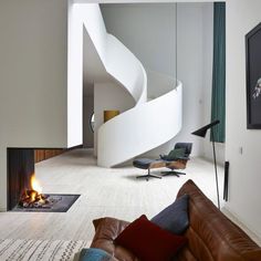 a living room filled with furniture and a fire place in front of a spiral staircase